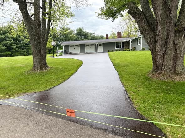 The same curved ranch driveway sealed black with the edges cut clean against the grass