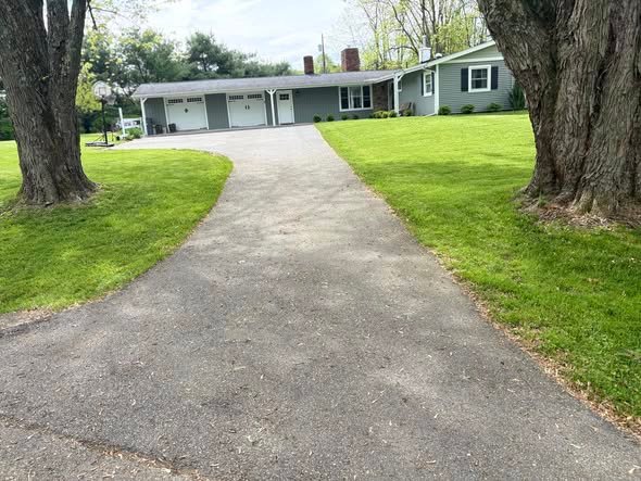 Long curved driveway at a ranch house, gray and worn before seal coating